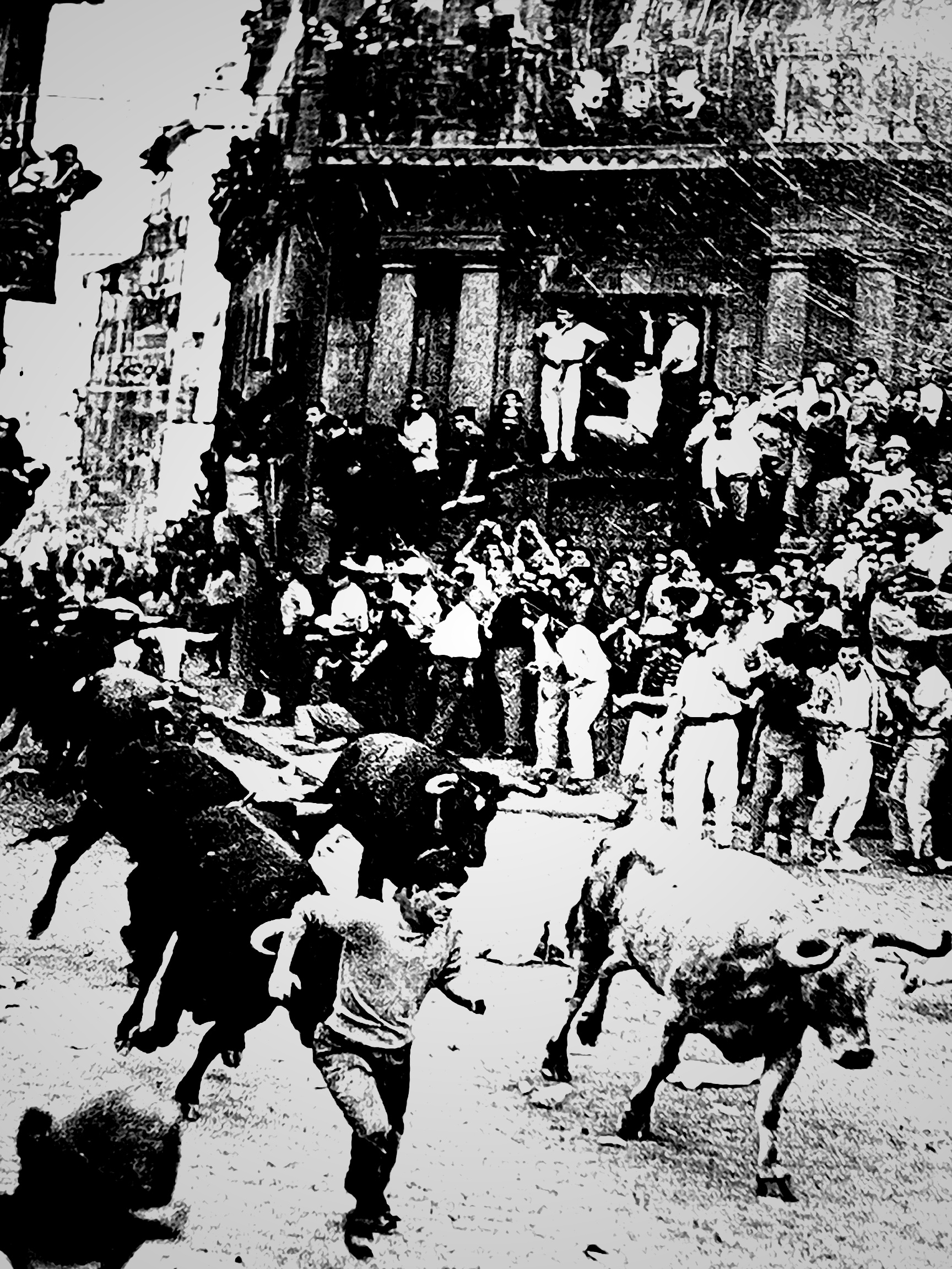 Black-and-white photograph of runners and bulls in a crowded Pamplona street